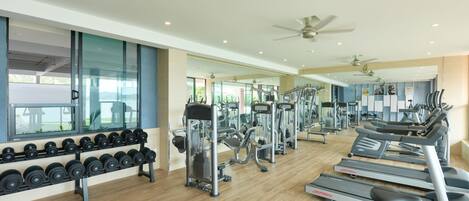 A gym with treadmills, elliptical machines, and dumbbells.
