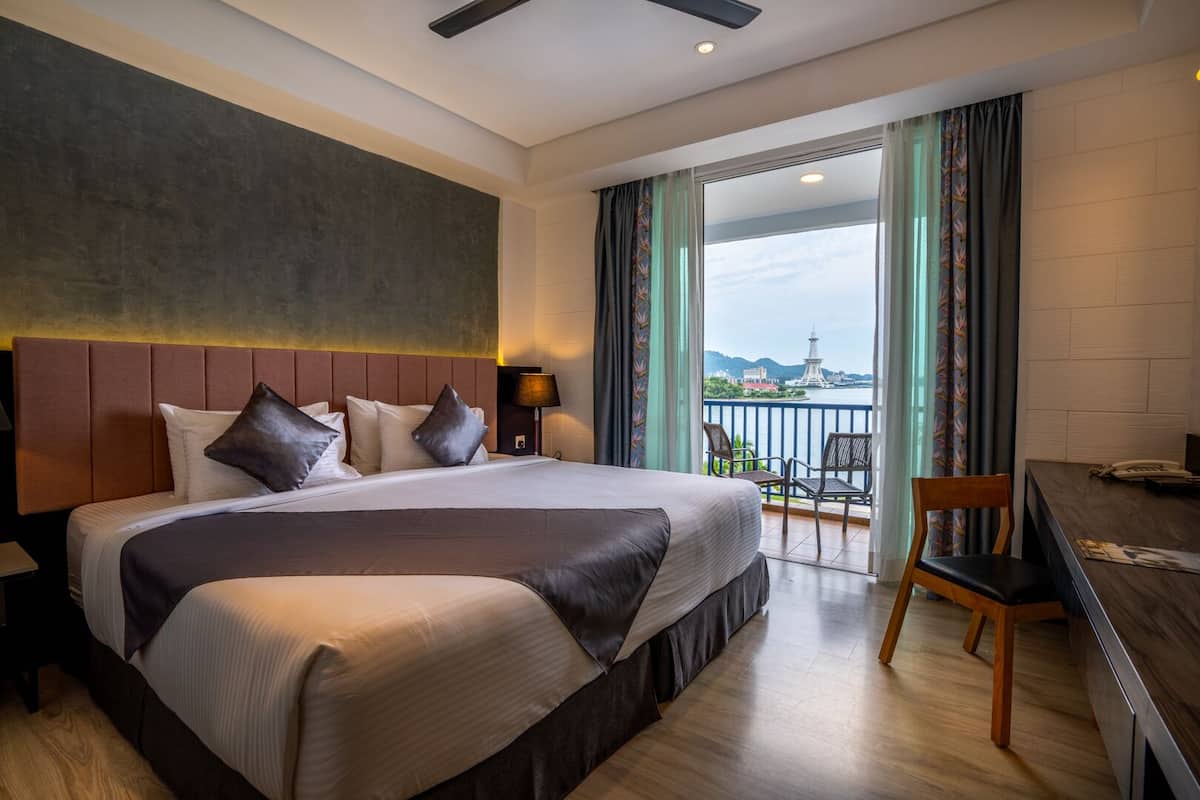 Une chambre d’hôtel avec un grand lit, un bureau et une vue sur le paysage urbain par la fenêtre.