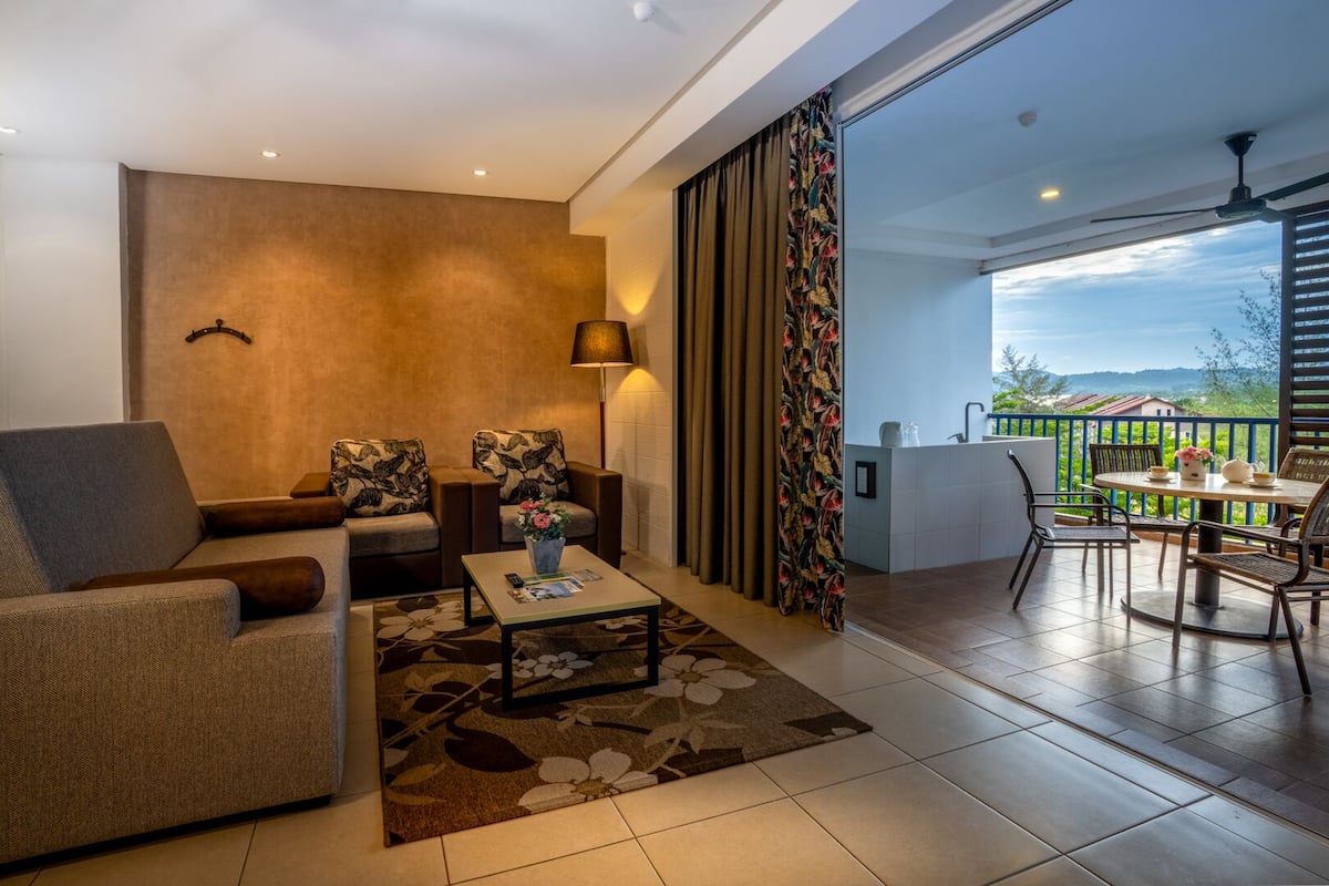 Un salon moderne avec un canapé, des fauteuils, une table basse et un balcon offrant une vue agréable.