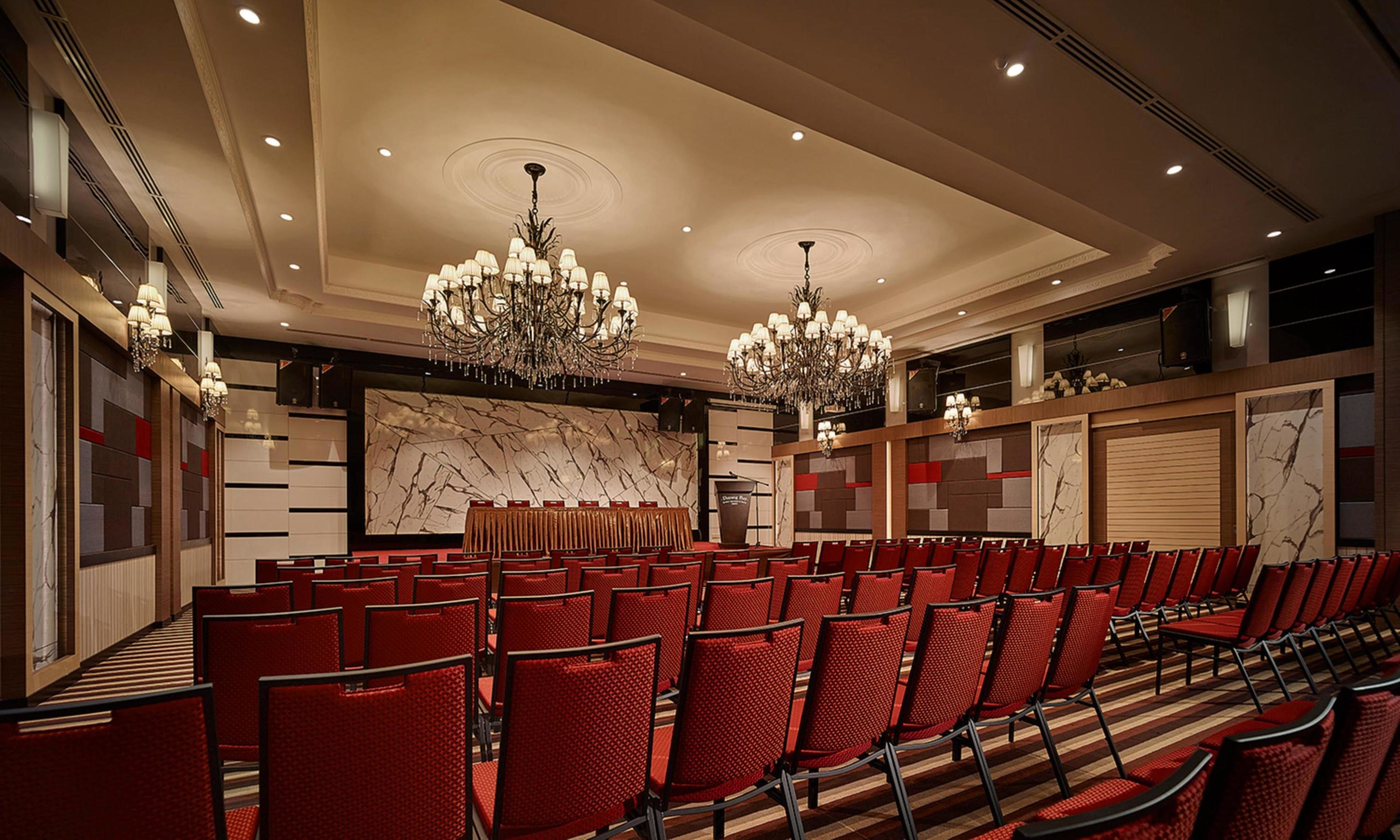A conference room with red chairs, chandeliers, and marble wall panels.