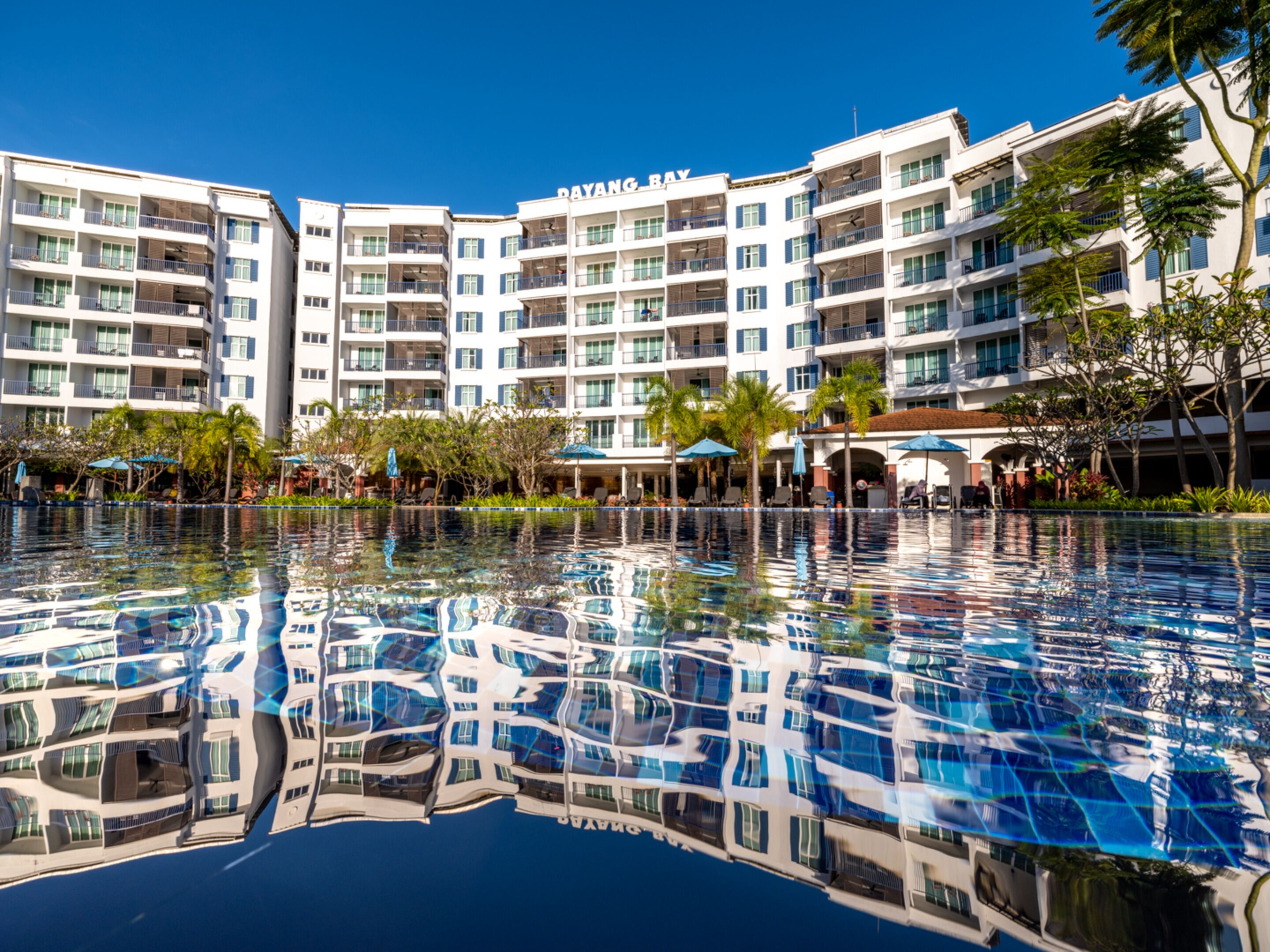 A hotel with a large pool reflecting the building's architecture.