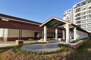 A modern building with a covered entrance, a stone base, and a clear sky.