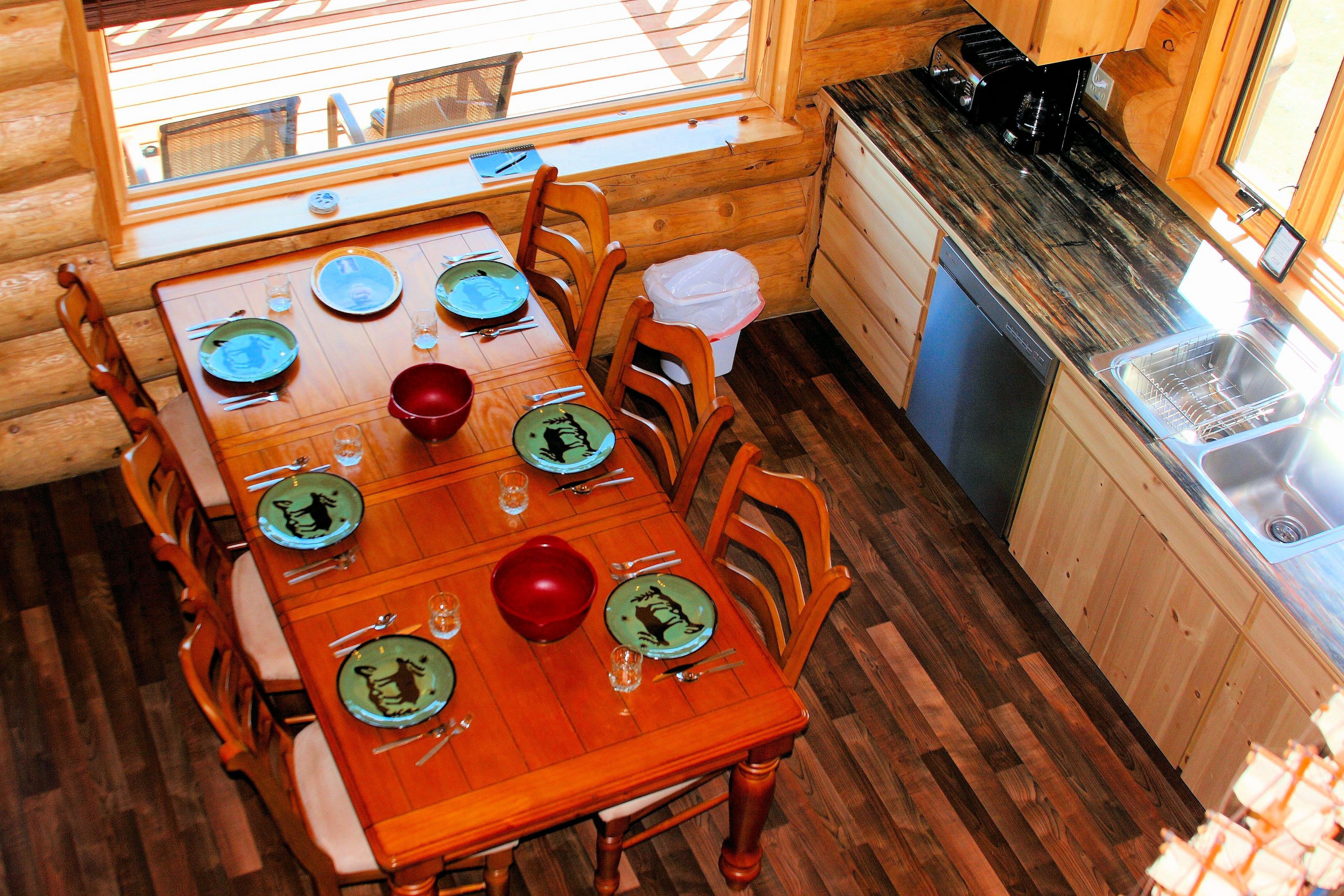 A wooden dining table set with plates, glasses, and cutlery.