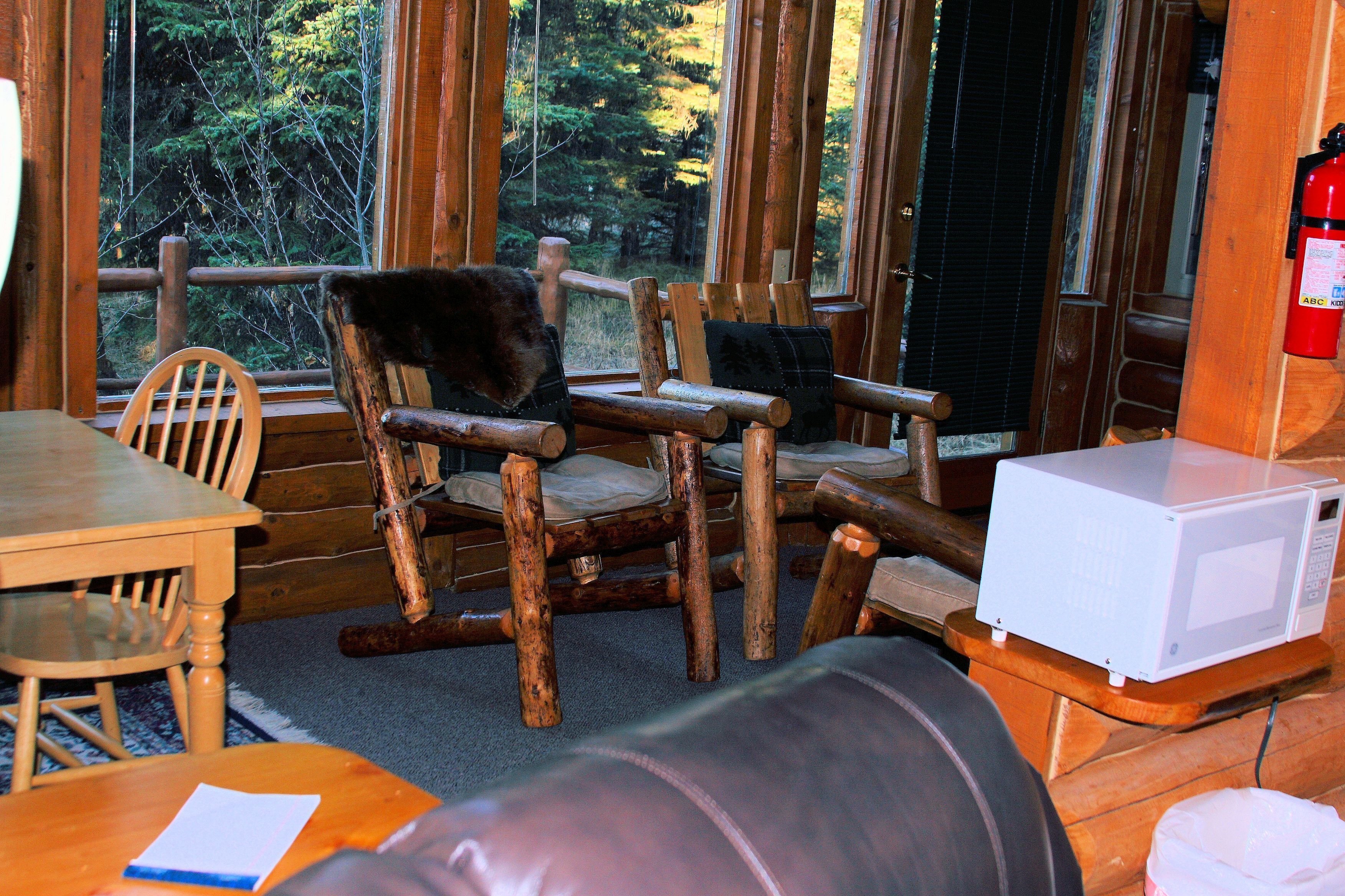 A rustic cabin interior with wooden furniture, a dining table, and a white microwave.