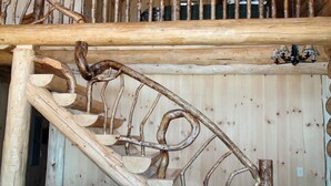 Una escalera espiral de madera con un diseño rústico, construida con troncos y ramas.