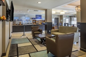 A hotel lobby with seating areas, a breakfast bar, and a reception desk.