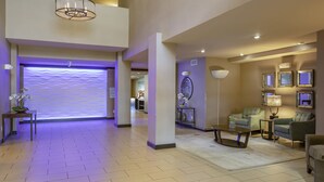 A spacious lobby with a modern design, featuring a reception desk, seating area, and decorative elements like a wall with a circular pattern and a large vase with flowers. - Holiday Inn Express & Suites Indio - Coachella Valley by IHG (Indio)