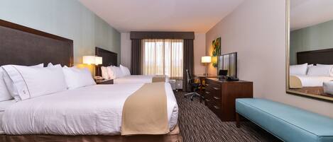 A hotel room with two beds, a desk, a chair, a television, and a large mirror.