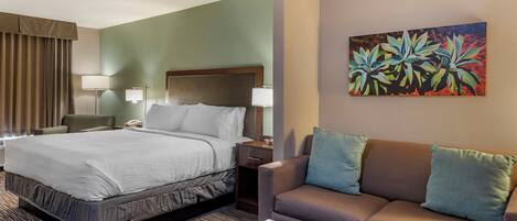 Una habitación de hotel con cama, sofá, mesa de centro y un cuadro en la pared.