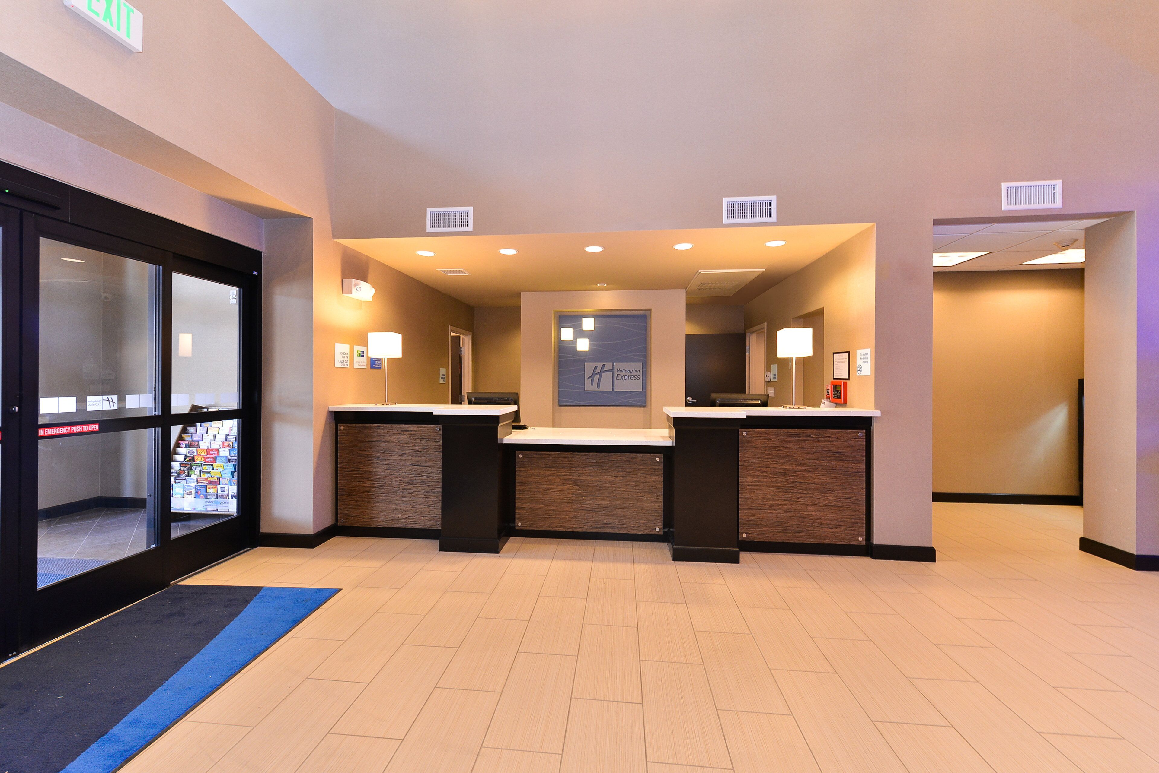 A hotel reception area with a glass door entrance, a reception desk, and a counter.