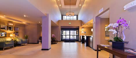 A spacious lobby with a reception desk, seating area, and a chandelier.