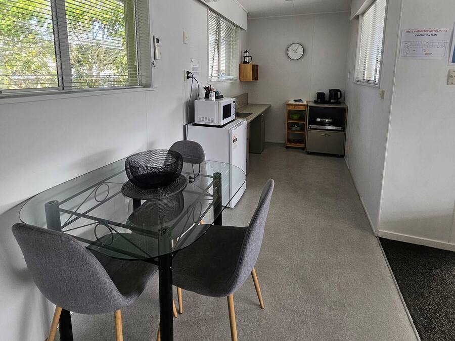 Una cocina compacta con microondas, cafetera y un reloj en la pared.
