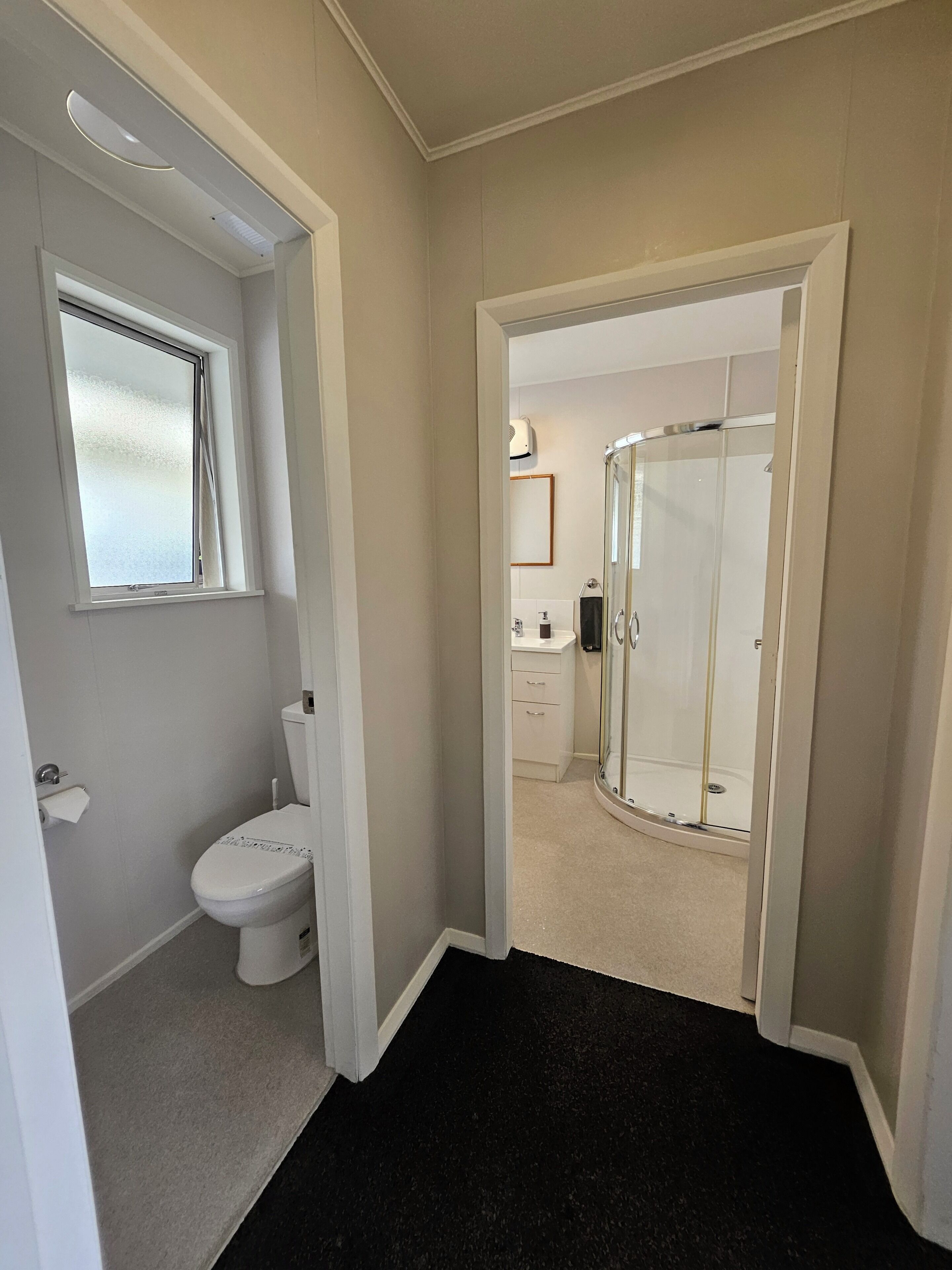 A bathroom with a toilet, a shower, and a window.