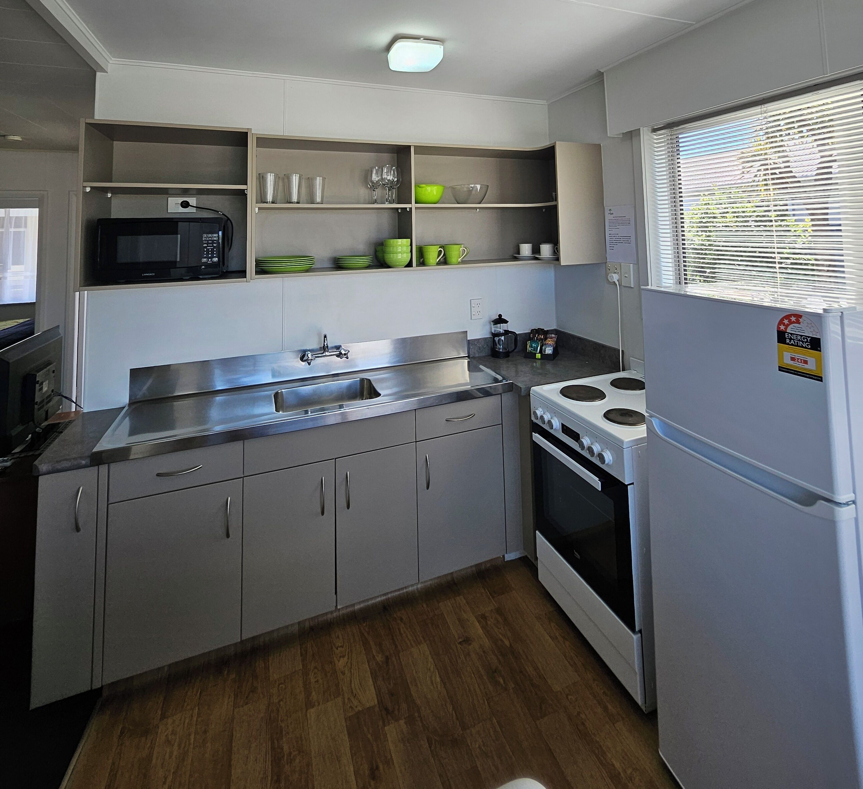 A compact kitchen with a microwave, sink, stove, and a refrigerator.