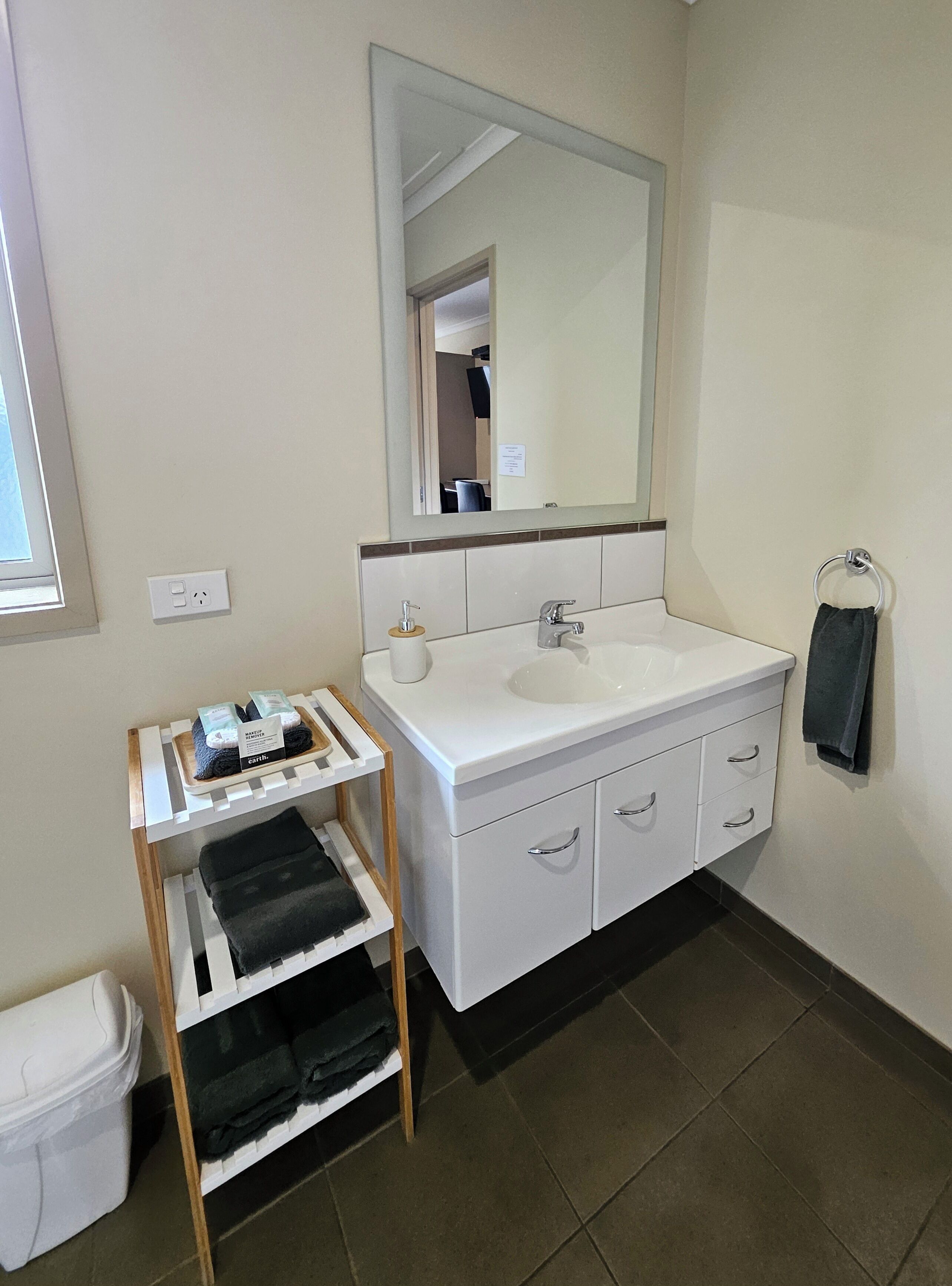 A bathroom with a white sink, mirror, and a towel rack.