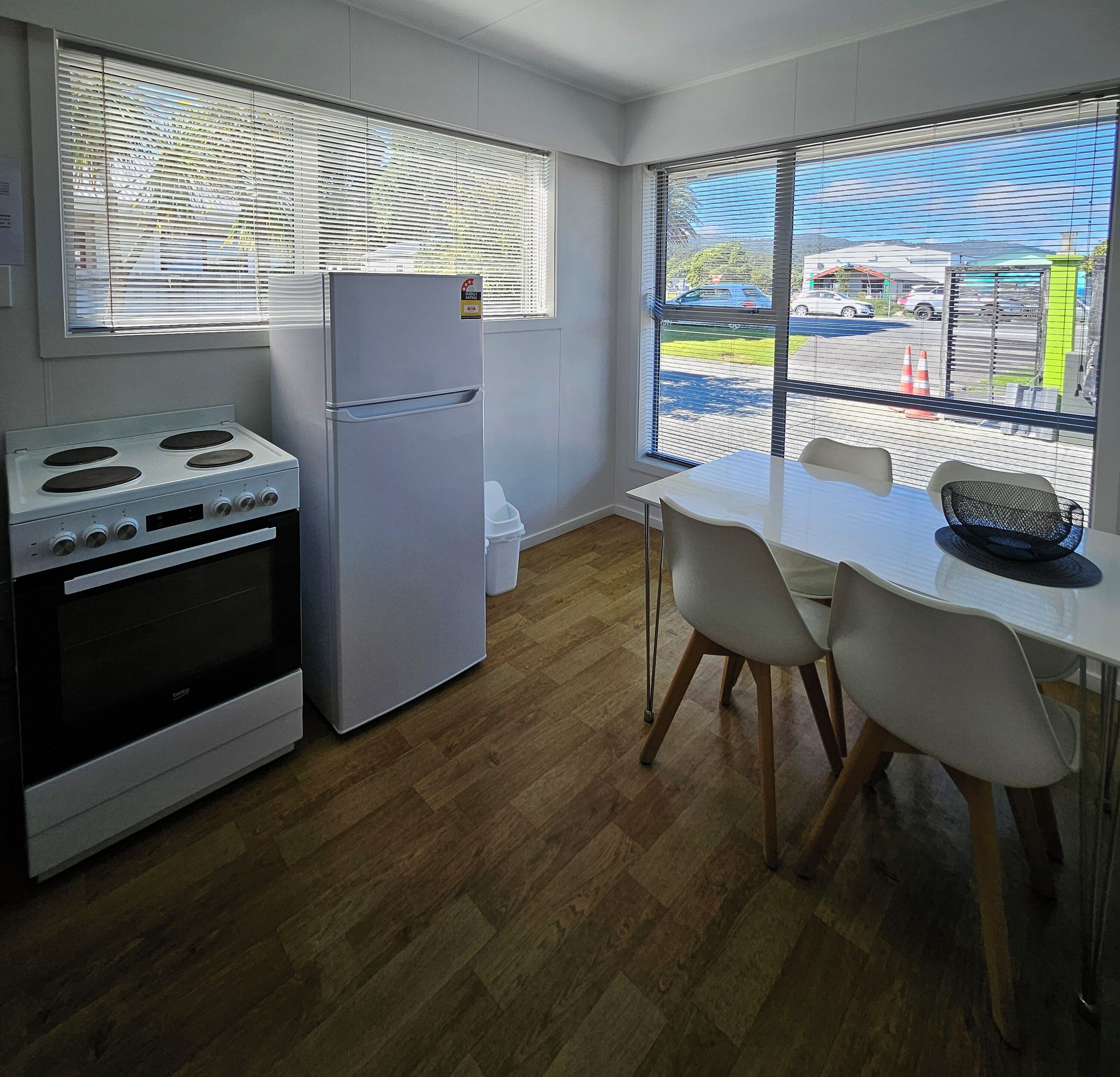 A compact kitchen with a refrigerator, stove, and dining table with chairs.