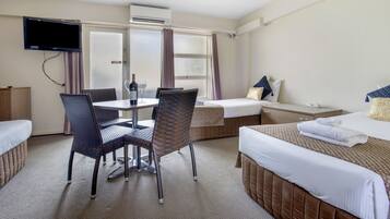 A hotel room with a bed, a desk, a chair, a television, and a window with curtains.
