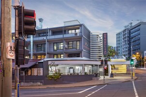 Et moderne hotel med glasfacade, flere etager og en tagterrasse.
