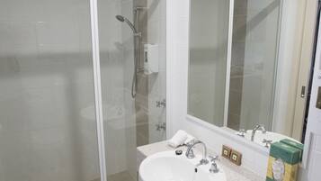 A bathroom with a glass-enclosed shower, a sink with a countertop, and a mirror above it.