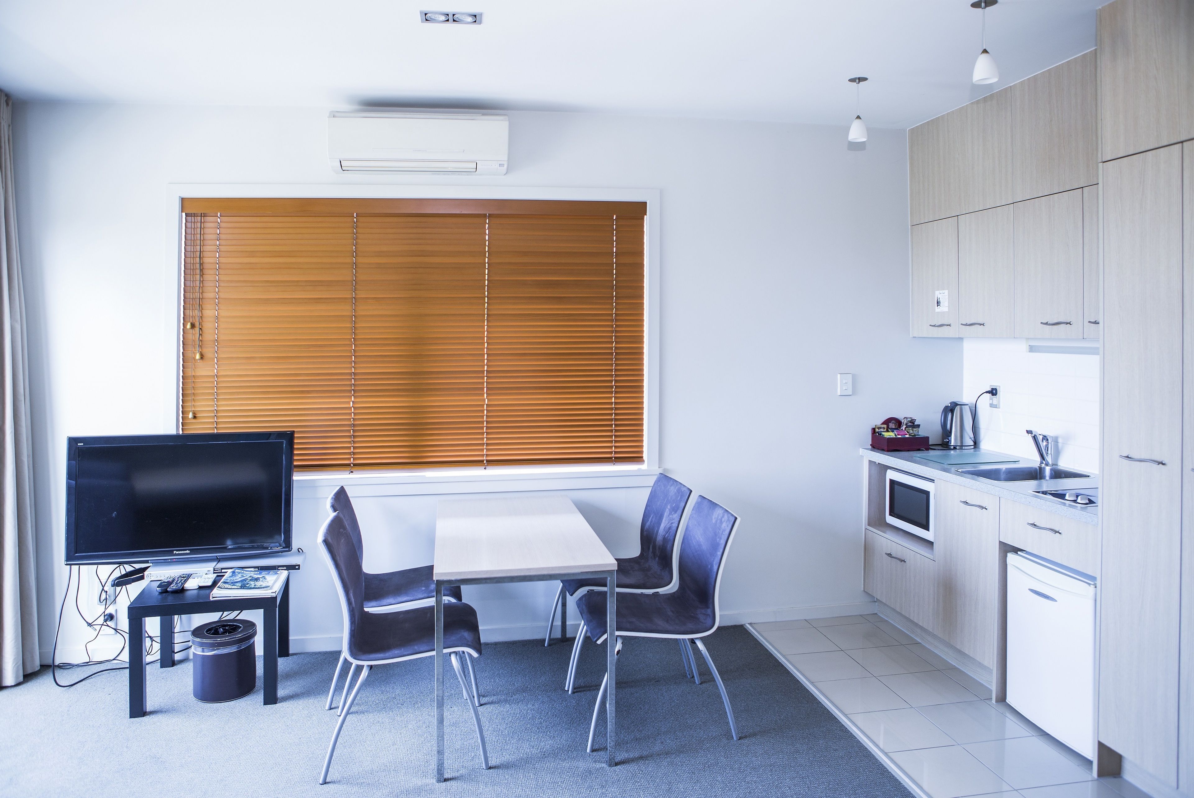 Een moderne keuken met een eethoek, met een flatscreen-tv, een tafel en twee stoelen.