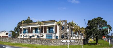 Een modern hotel met een gevel van natuursteen, grote ramen en een bord met de tekst 'waves'.