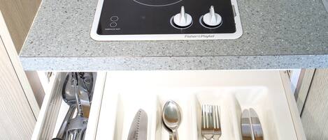 A kitchen with a built-in induction cooktop and a drawer organizer with utensils.