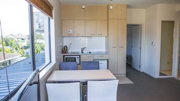 Una cocina moderna con armarios de madera, una mesa de comedor con sillas y vistas al exterior a través de amplias ventanas.