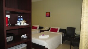Une chambre d’hôtel avec deux lits, un bureau, une chaise, un mini-bar et une petite télévision.
