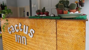 Un comptoir d’accueil avec une enseigne indiquant « Cactus Inn » et divers cactus en pot disposés sur le dessus.