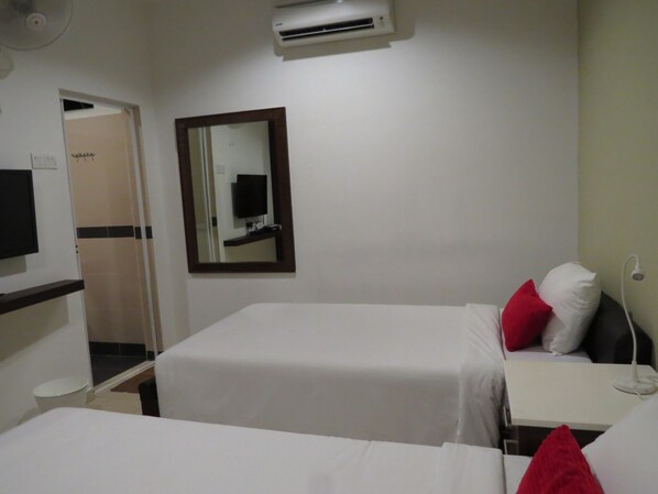 A hotel room with two beds, a TV, a mirror, and an air conditioning unit.