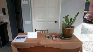 Une table recouverte d’une nappe marron, un cactus en pot et quelques magazines.