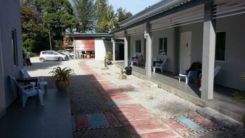 Un'area esterna coperta con posti a sedere e un vialetto sterrato.