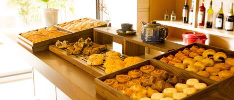 A buffet with various pastries and a selection of wine bottles.