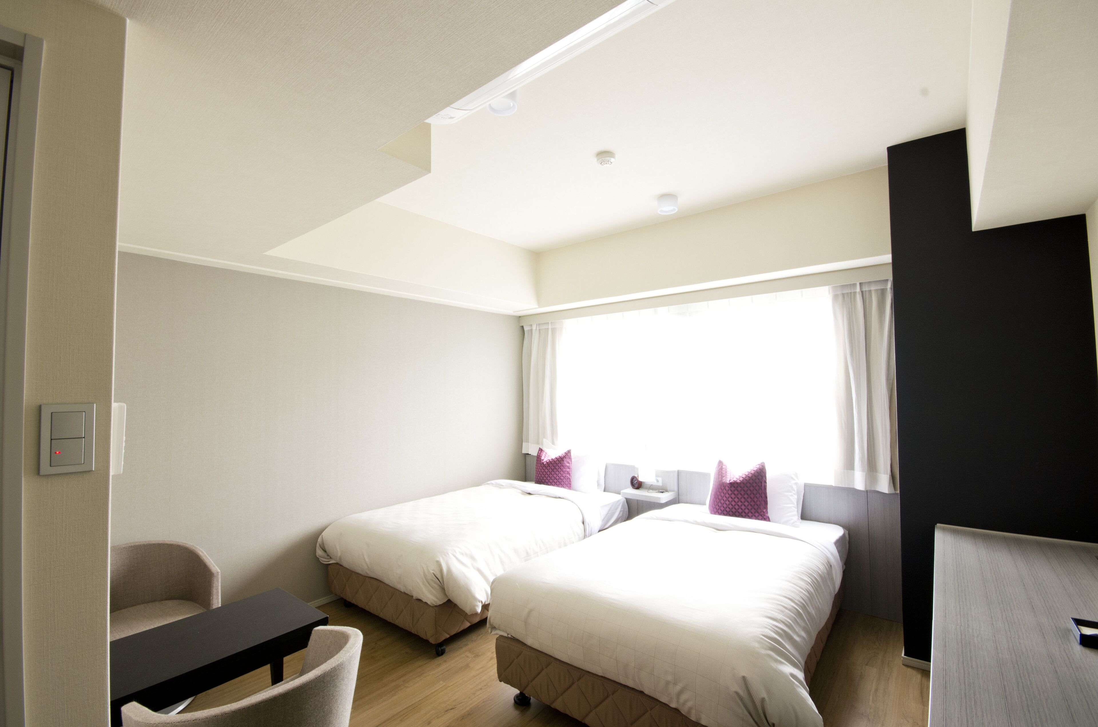 Habitación de hotel con dos camas, un escritorio y una silla.