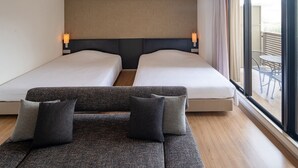A hotel room with two beds, a sofa, and a balcony with a table and chairs. - Sakura Terrace (Kyoto)