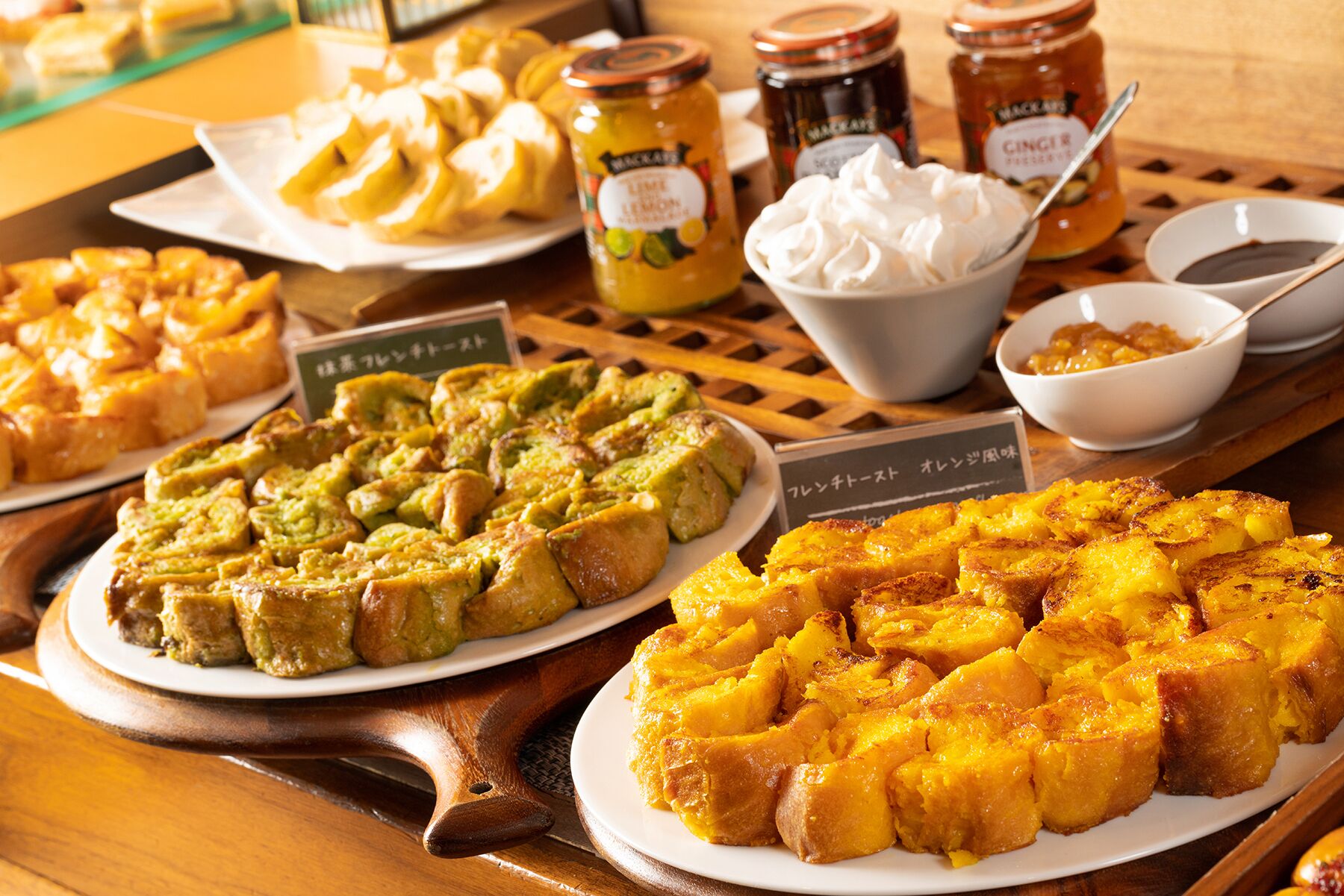 A variety of baked goods on a wooden table, including pies and pastries, with labels in a foreign language.