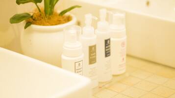 A bathroom with a bathtub, a potted plant, and several bottles of toiletries.