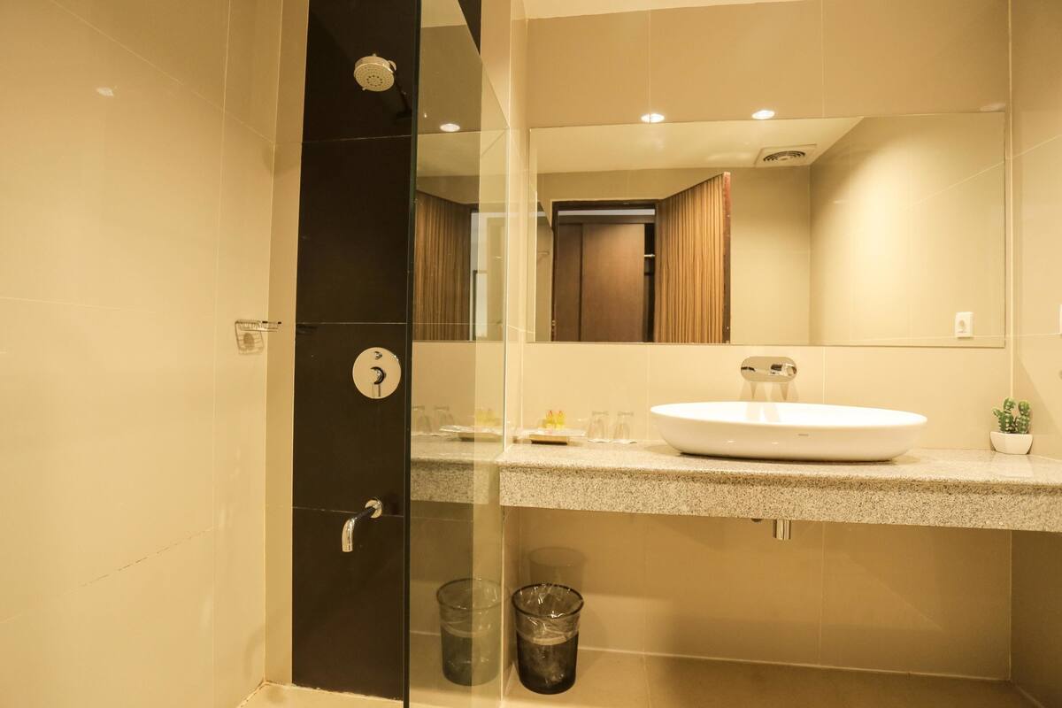 Un baño moderno con cabina de ducha de vidrio, un lavamanos blanco y un espejo sobre él.