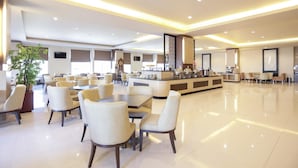 A spacious hotel lobby with multiple seating areas, a central counter, and a large potted plant. - Grand Asia Hotel (Makassar)