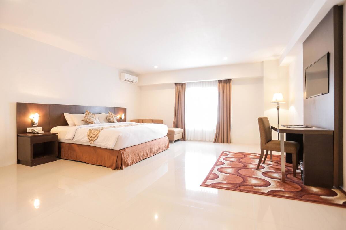 Una habitación de hotel moderna con una cama grande, un escritorio y una silla.