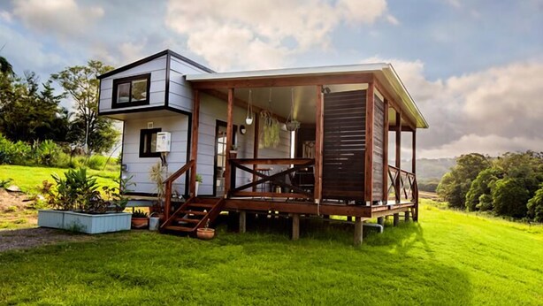 Een modern huis met een houten terras, een trap en een kleine tuin.