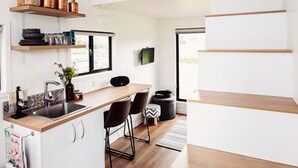Een moderne keuken met een houten aanrecht, witte kastjes en een hangende lamp.