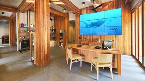 A reception area with wooden paneling, a large blue aquarium wall, and a reception desk with a computer. - Beach Club by Haad Tien (Koh Tao)