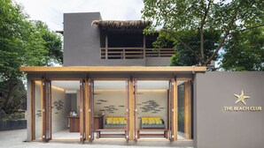 A modern building with a wooden entrance, a balcony, and a wall with a starfish logo. - Beach Club by Haad Tien (Koh Tao)