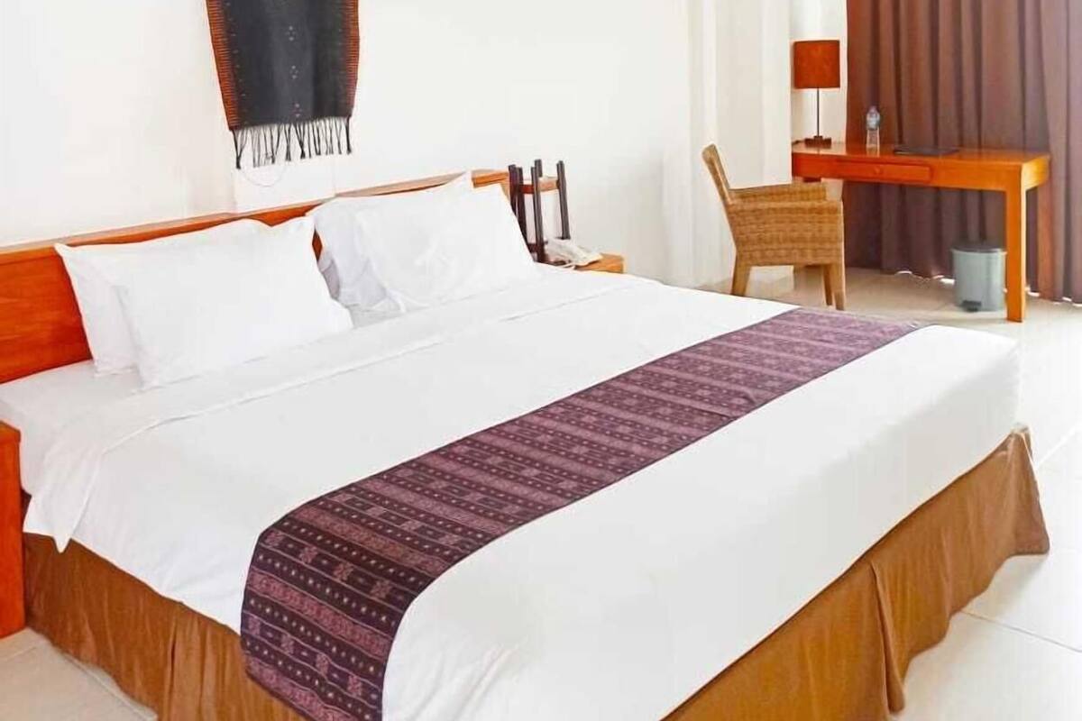 Ein Hotelzimmer mit Bett, Schreibtisch, Stuhl und einem großen Fenster mit Vorhängen.