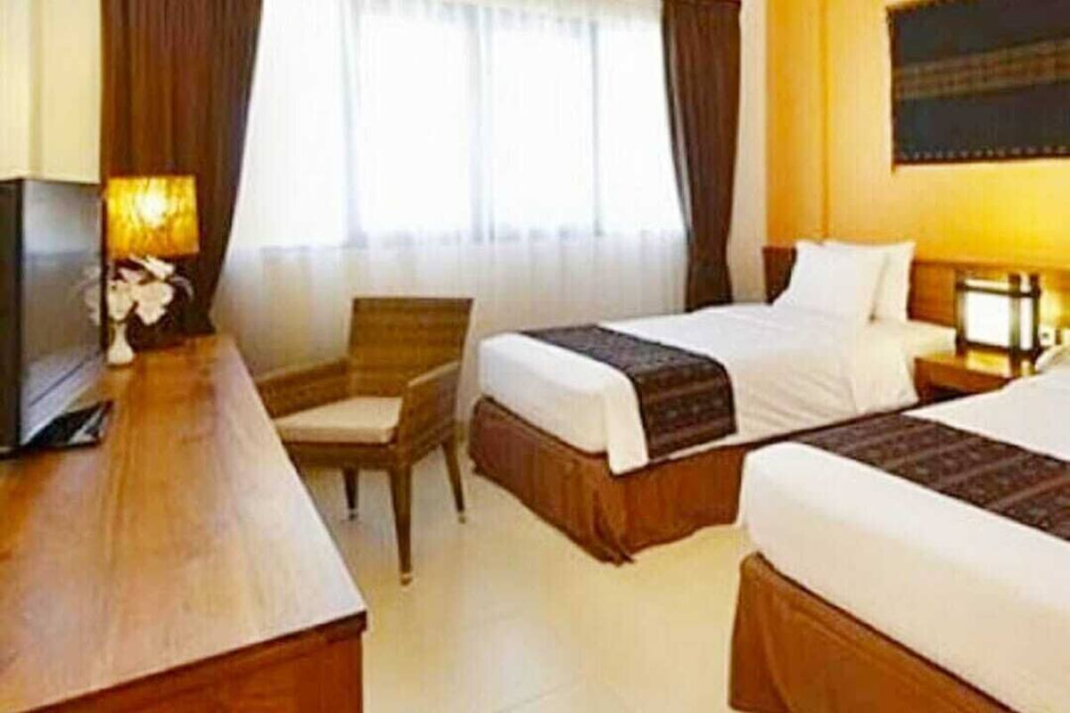 Ein Hotelzimmer mit zwei Betten, einem Schreibtisch, einem Stuhl und einem Fernseher.