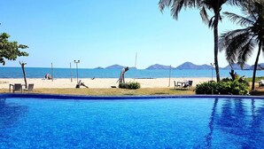 Une piscine avec vue sur une plage et des montagnes en arrière-plan.
