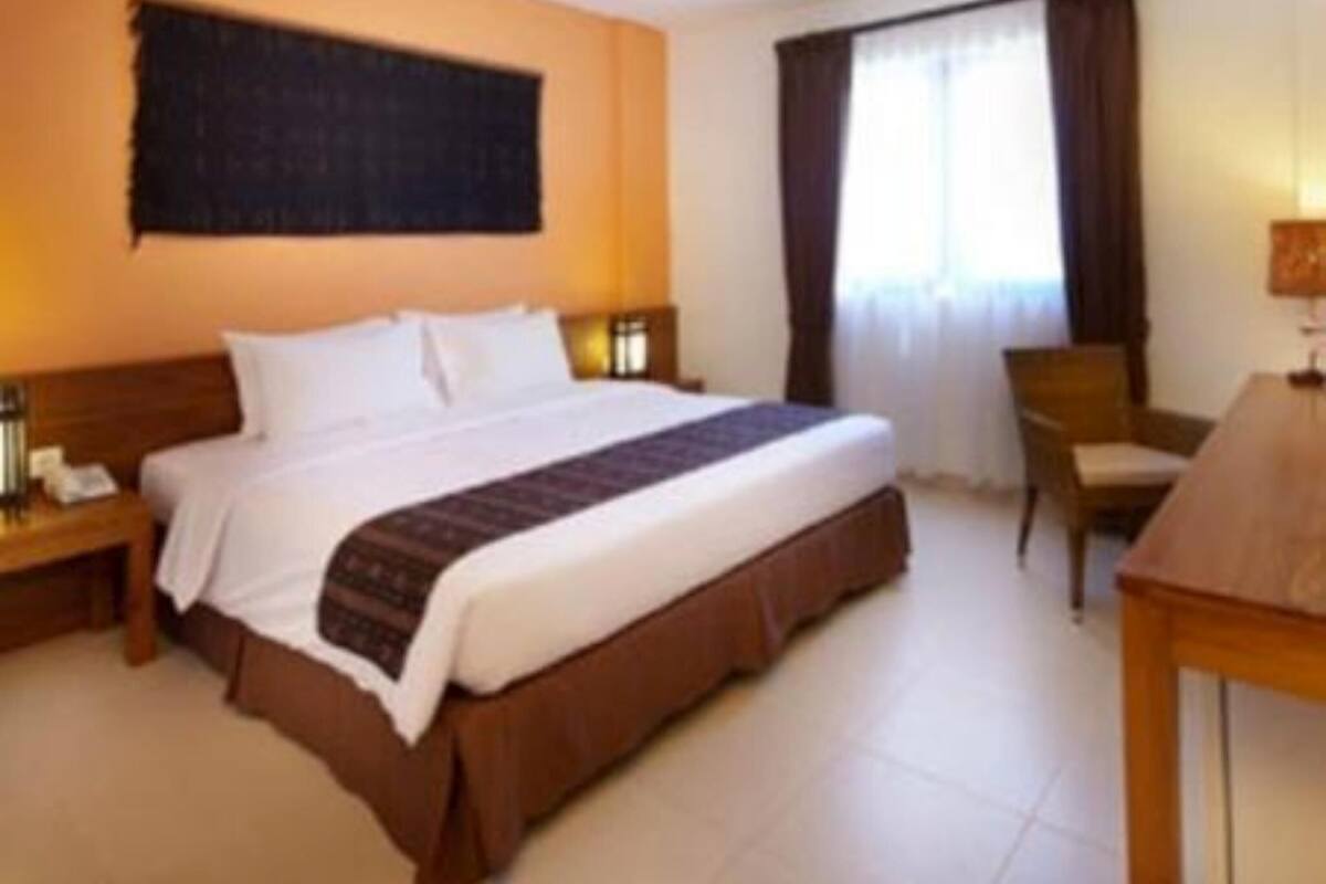 Ein Hotelzimmer mit einem großen Bett, einem Nachttisch aus Holz, einem Schreibtisch und einem Stuhl.