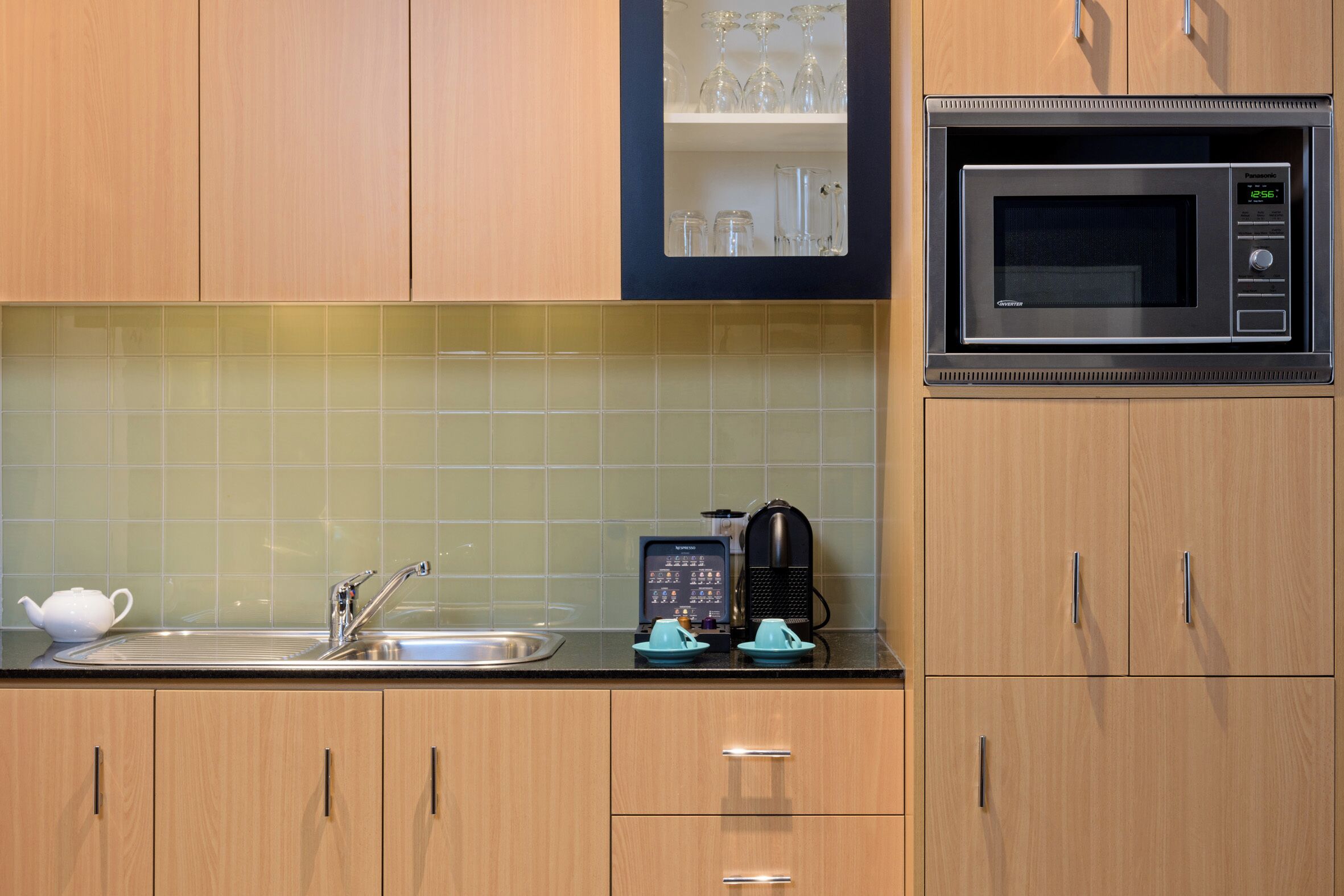 A kitchen with a microwave, a coffee maker, and a sink.