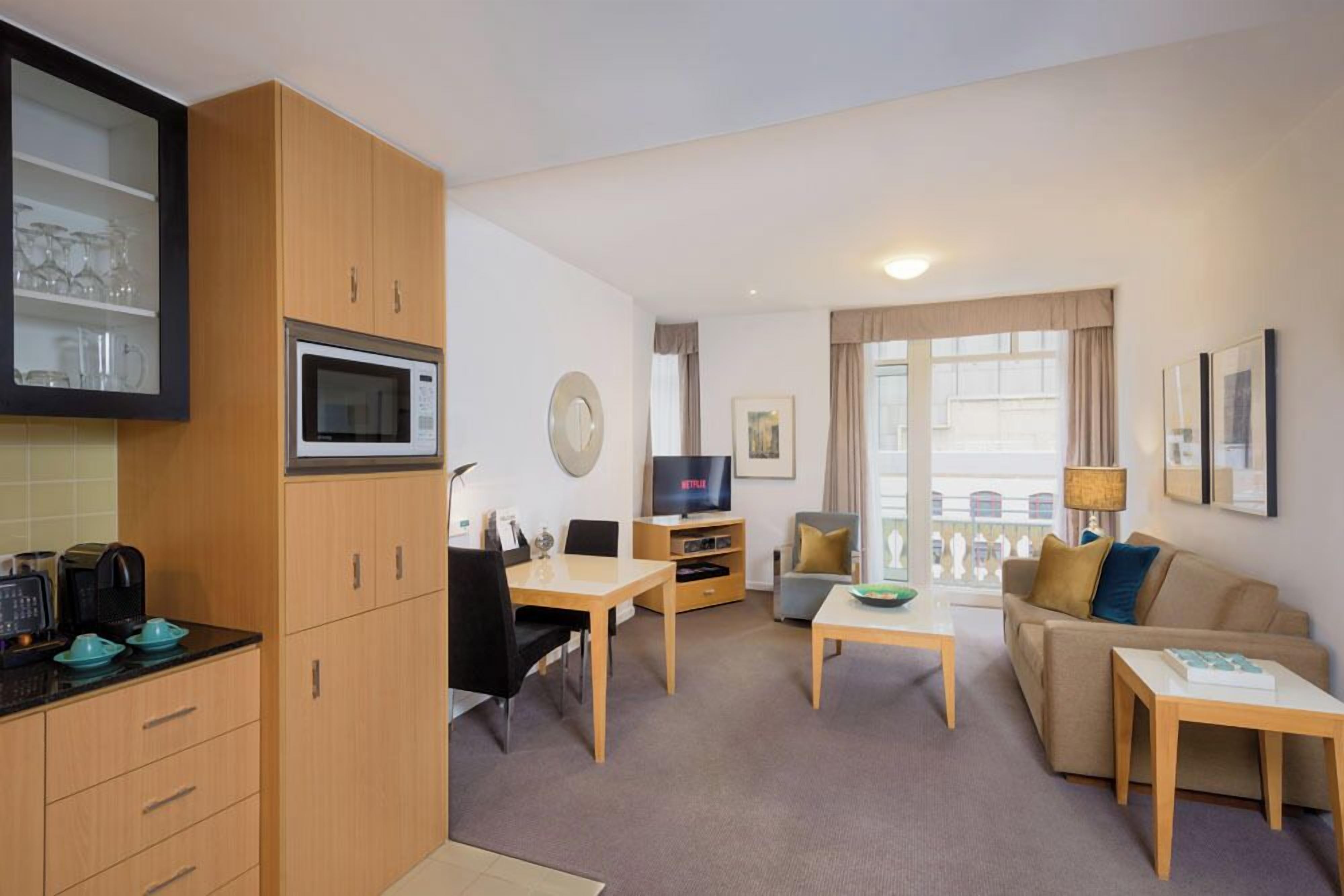 A compact living space with a kitchenette, a dining area, a sofa, and a TV.